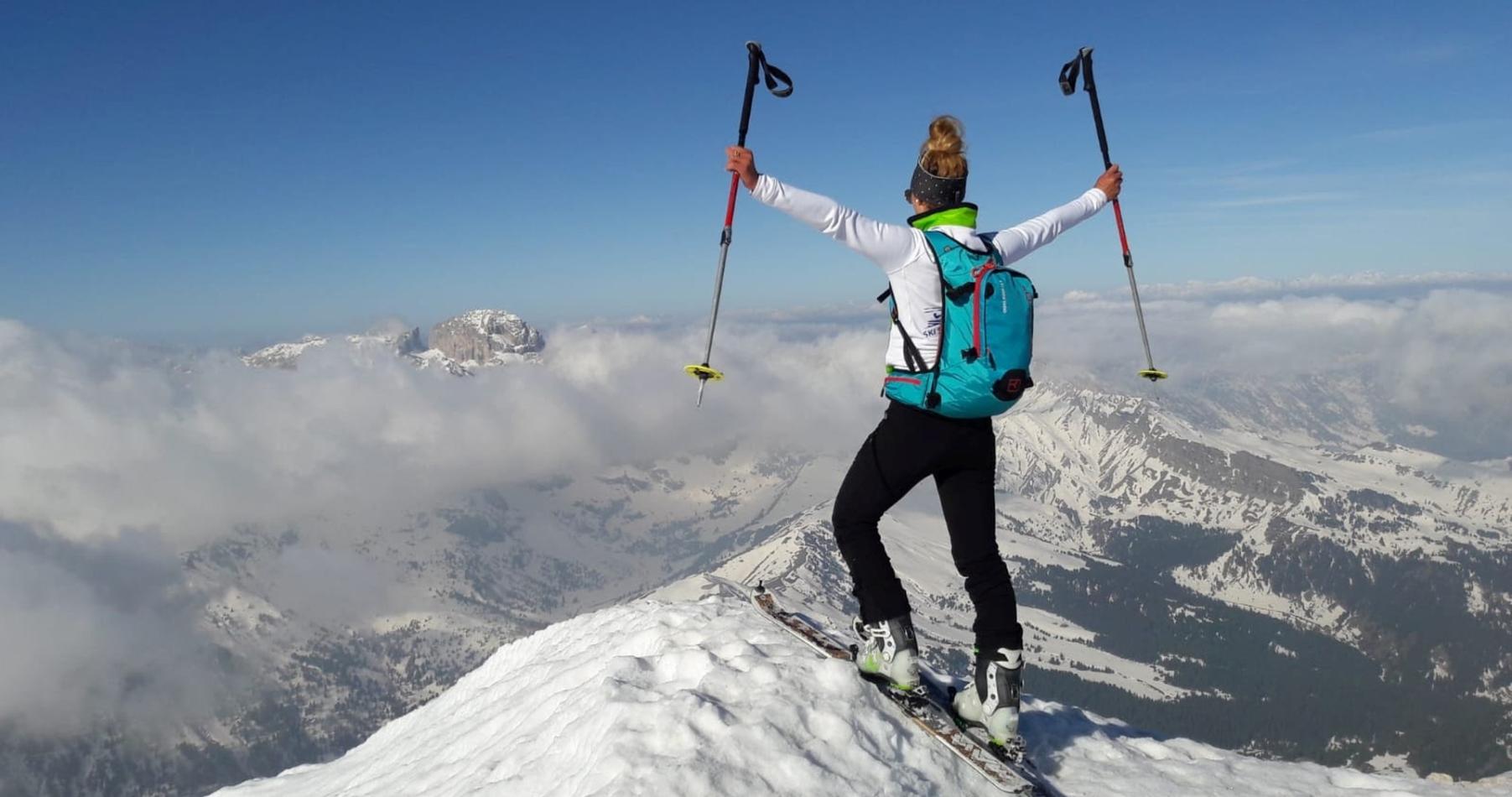 Eine Skitourengeherin freut sich über die Aussicht am Gipfel