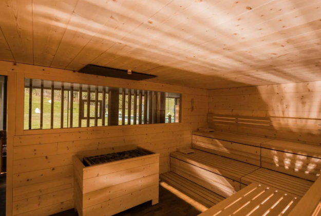 Wooden bio sauna in the wellness area of Hotel Floralpina with warm lighting and a panoramic window