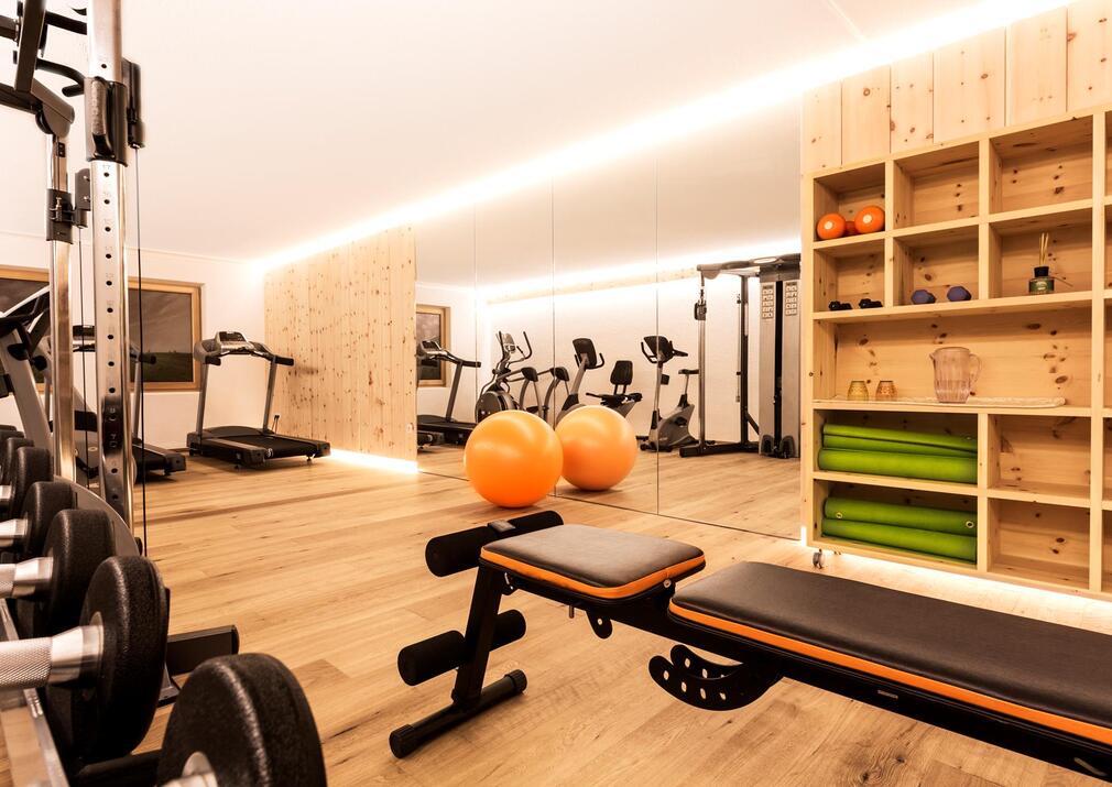 Fitnessraum im Sporthotel Floralpina mit Hanteln, Trainingsbank und modernen Fitnessgeräten