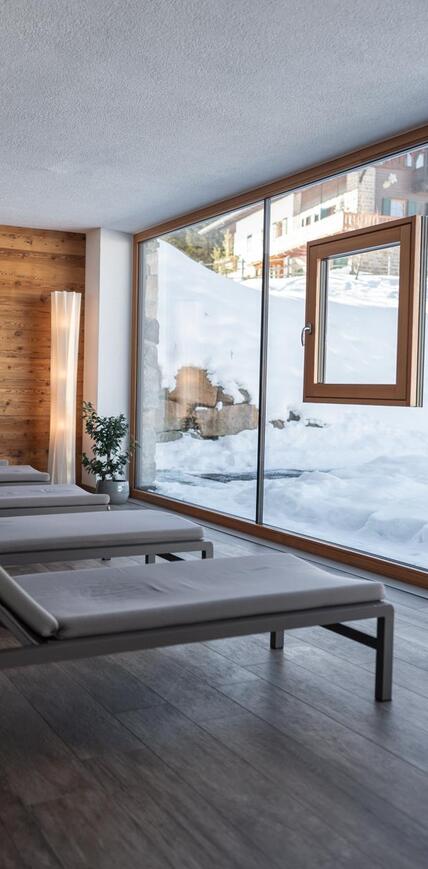 Ruheraum im Wellnesshotel Floralpina mit Liegen und Panoramablick auf die verschneite Bergwelt