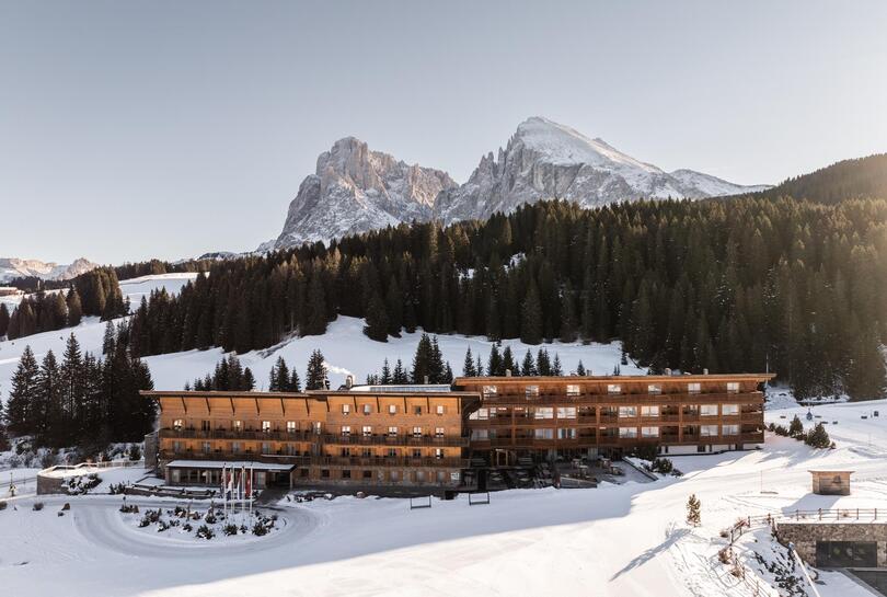 Vista esterna innevata dell'Hotel Floralpina con lo sfondo delle Dolomiti