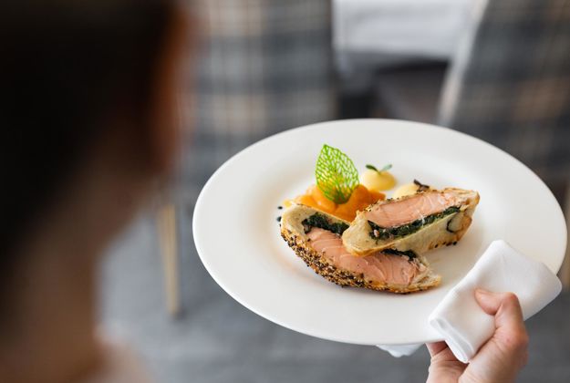 A waiter is serving a main dish in our hotel on the Seiser Alm