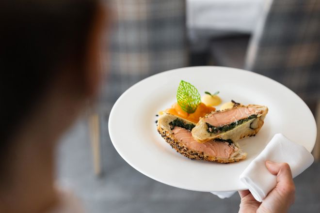 Ein Kellner serviert ein Hauptgericht in unserem Sporthotel in den Dolomiten