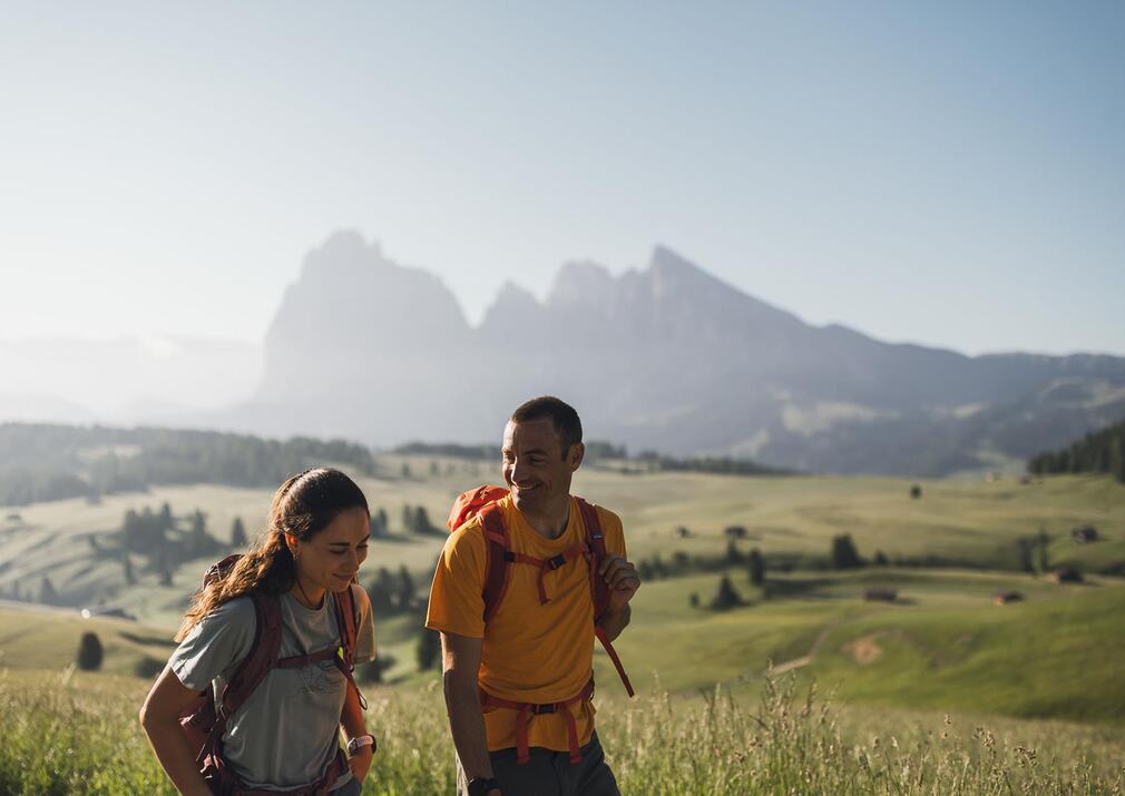 Wanderndes Paar auf der Seiser Alm Alpe di Siusi mit Blick auf Langkofel und Plattkofel in den Dolomiten