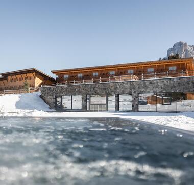 Vista esterna dell’hotel Floralpina con piscina riscaldata e panorama montano sull’Alpe di Siusi