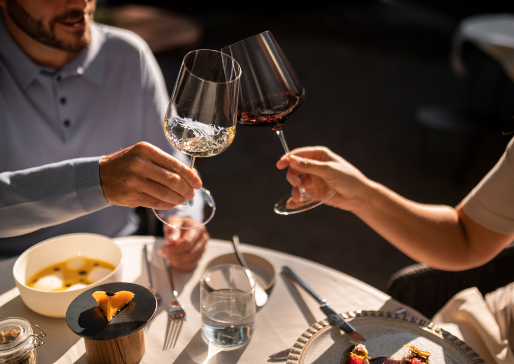 Two people are clinking their wine glasses