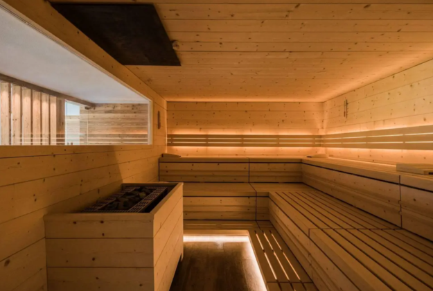 Sauna finlandese con panche in legno e illuminazione indiretta nell’area wellness dell’hotel Floralpina