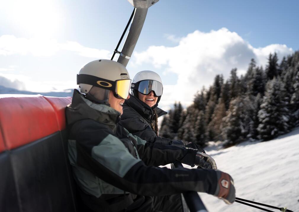 Two skiers riding a chairlift in the Alpe di Siusi Seiser Alm ski resort in the Dolomites