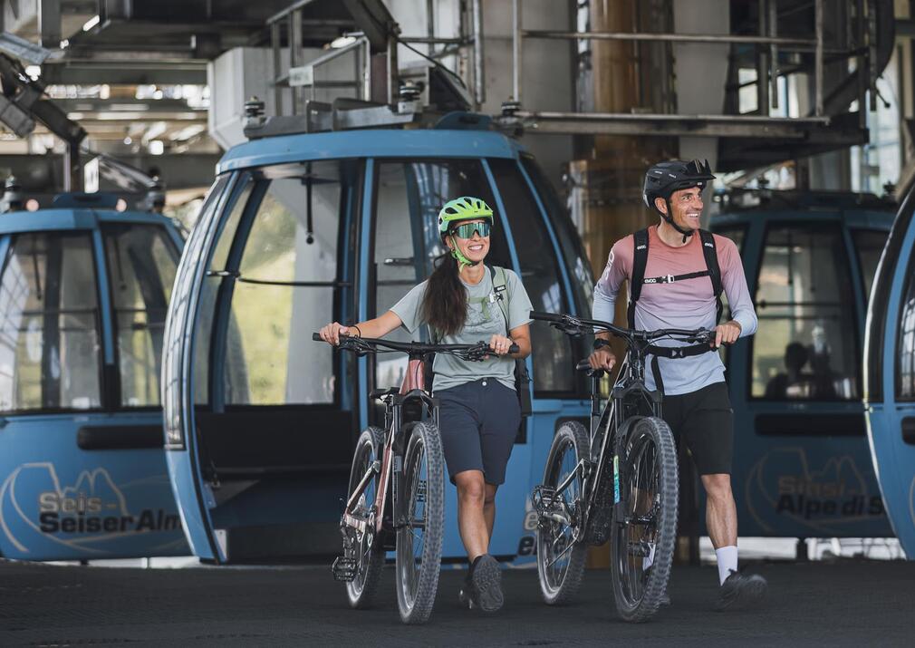 Couple with e-bikes at the Seiser Alm Alpe di Siusi cable car station ready for a mountain bike tour