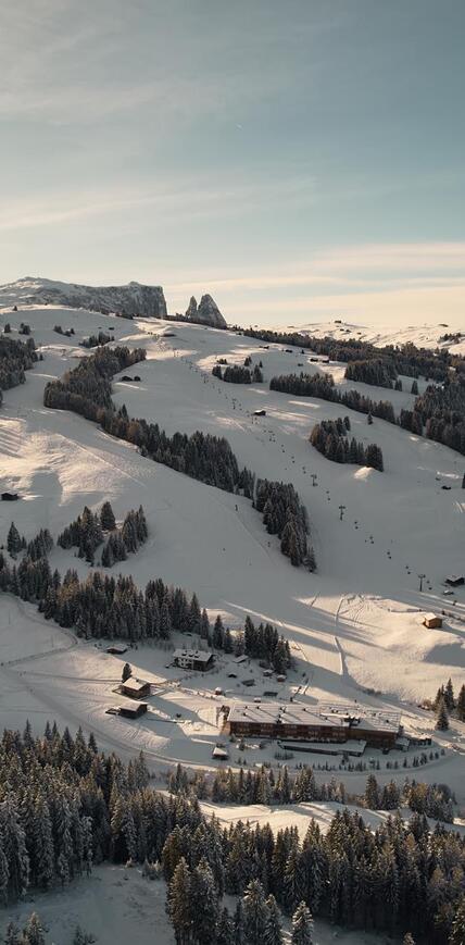 Winterpanorama mit dem Sporthotel Floralpina auf der Seiser Alm, verschneiten Skipisten und Dolomiten
