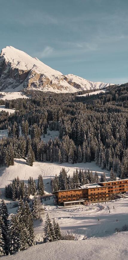 Winter aerial view of Sporthotel Floralpina on Seiser Alm with Langkofel and Plattkofel in the snow